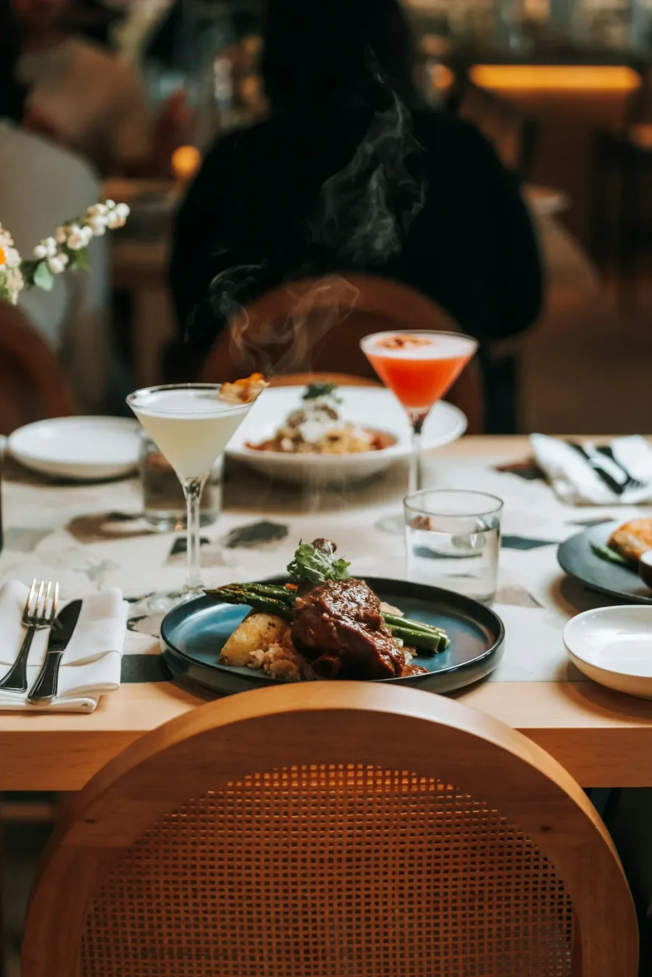 Plated dinner with vegetables and cocktails on a restaurant table; contextual photograph, not a photograph of No current player hangout is documented