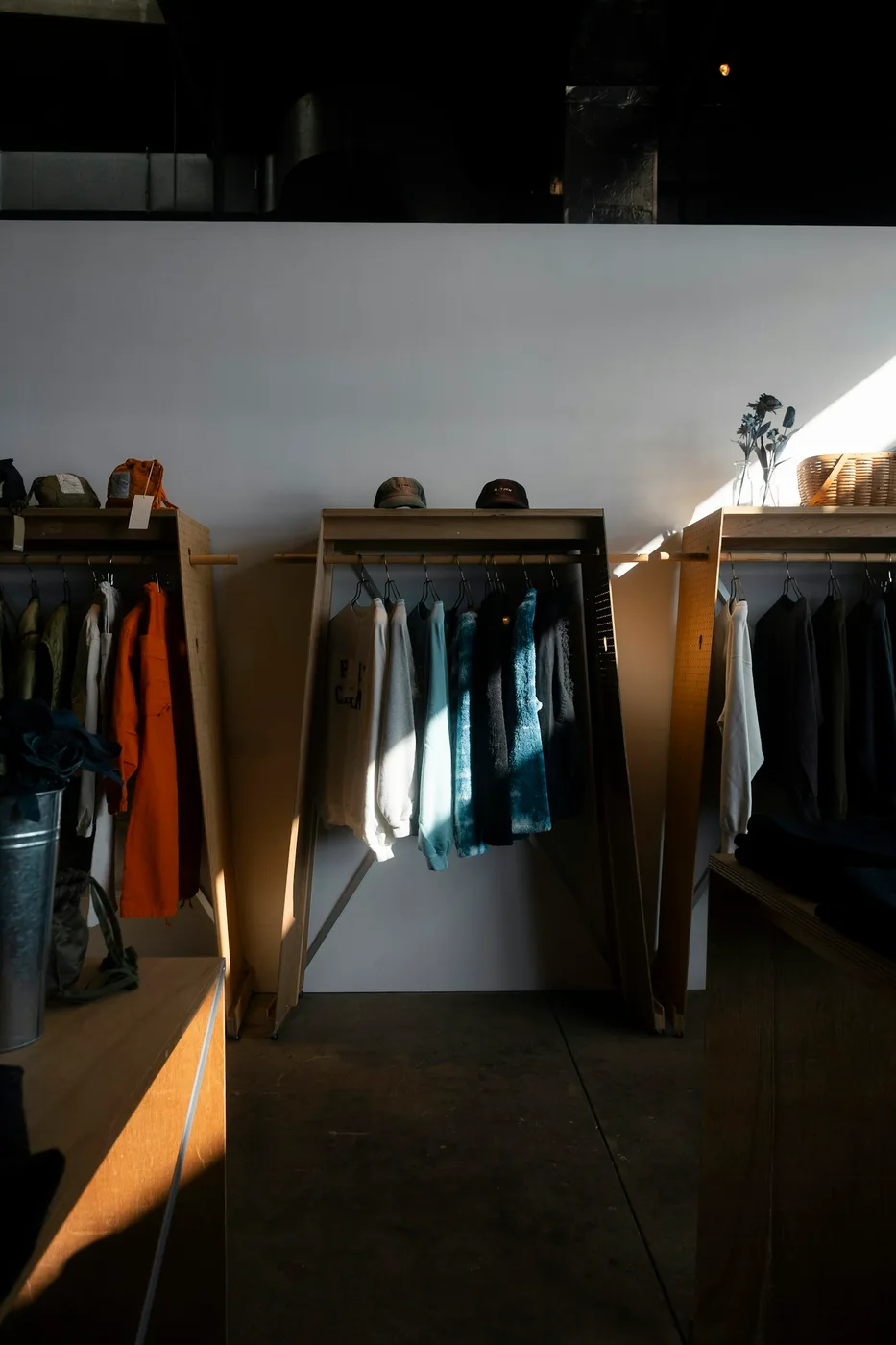 Clothing and hats displayed on wooden racks in a sunlit shop; contextual photograph, not a photograph of The tilted roof and the catwalks