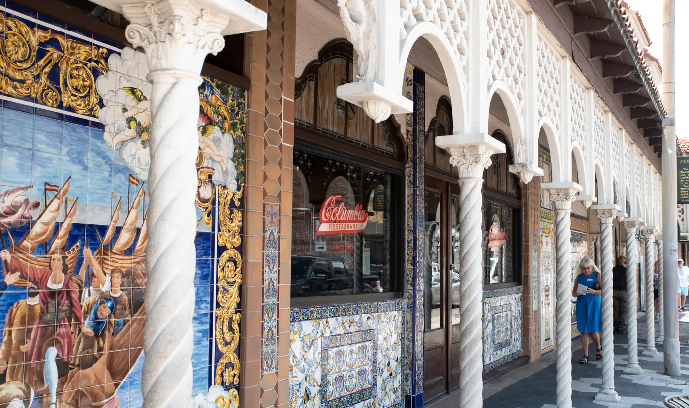The tiled Spanish-mural arcade and neon Columbia sign along the sidewalk outside the Columbia Restaurant in Ybor City