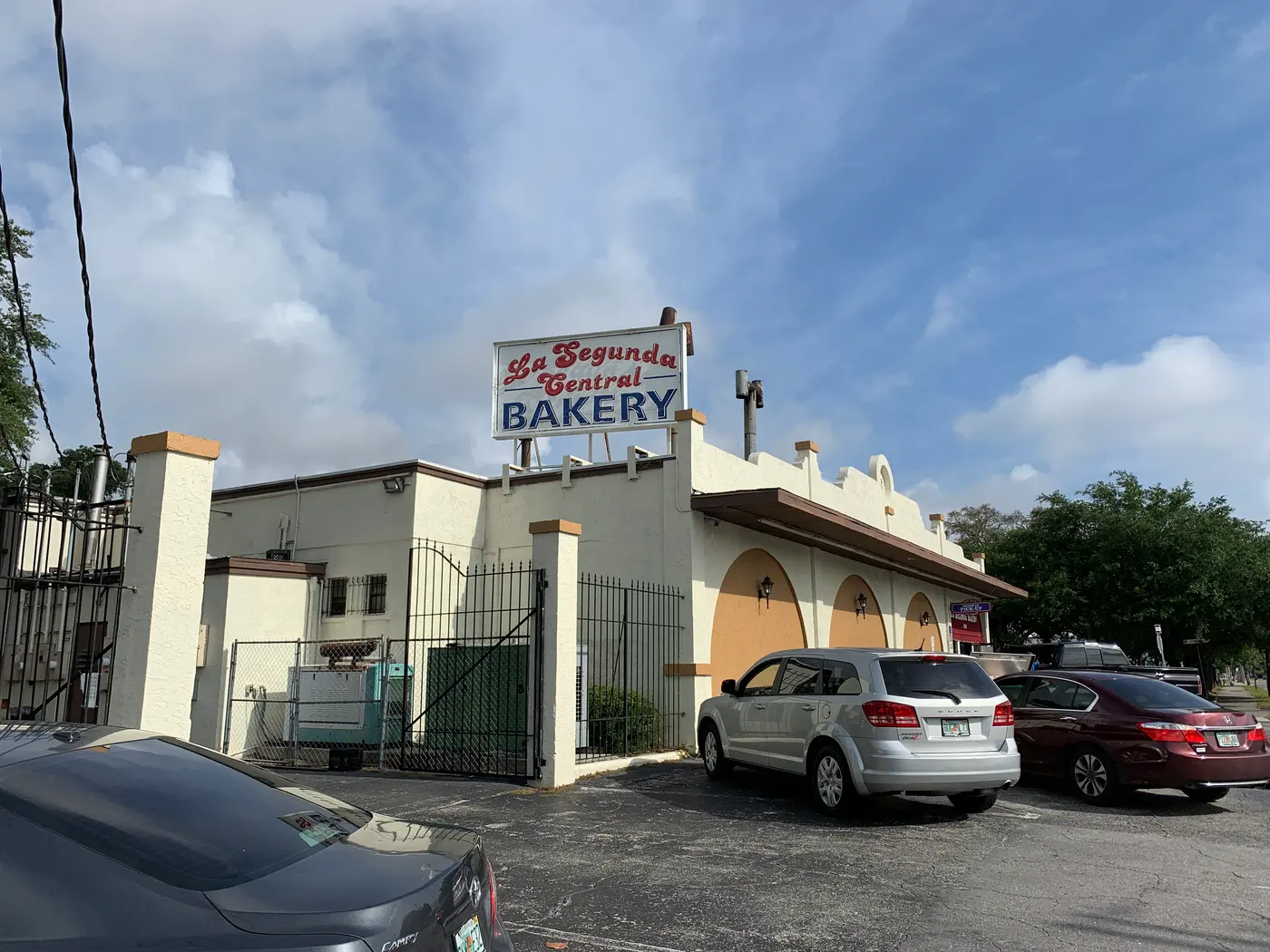 The stucco exterior of La Segunda Central Bakery in Ybor City, with its red lettered BAKERY sign and cars parked out front