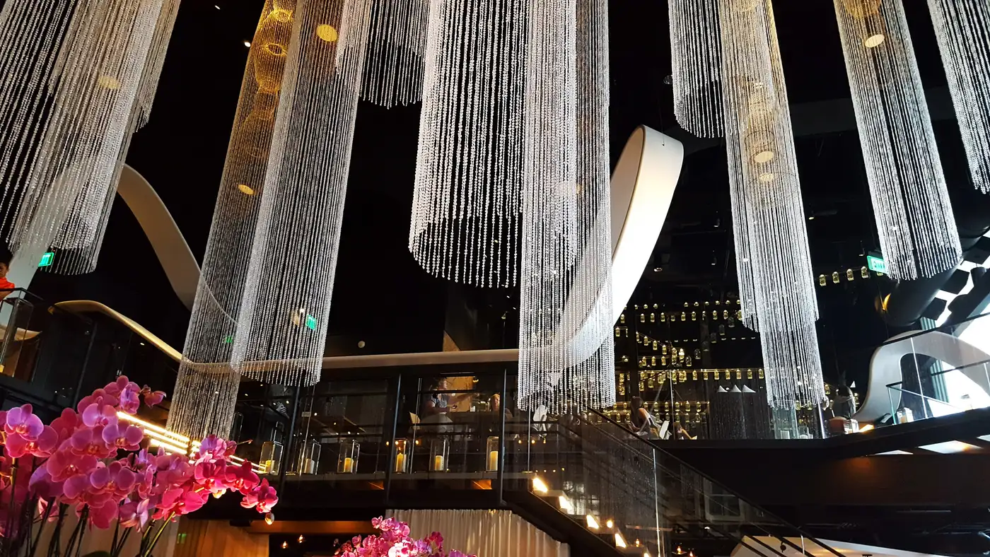 Morimoto Asia's dramatic cascading crystal-strand chandeliers over the restaurant's staircase and bar, with orchids in the foreground