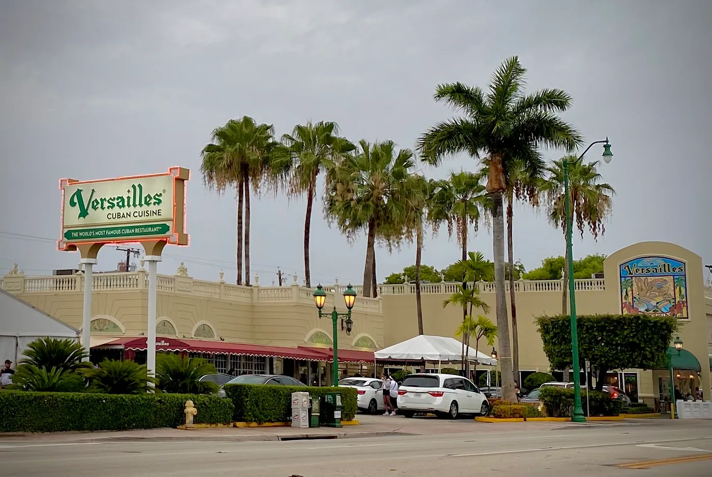 Versailles Restaurant's tall pylon sign reading Versailles Cuban Cuisine, The World's Most Famous Cuban Restaurant, standing in front of royal palms on Calle Ocho in Little Havana, Miami