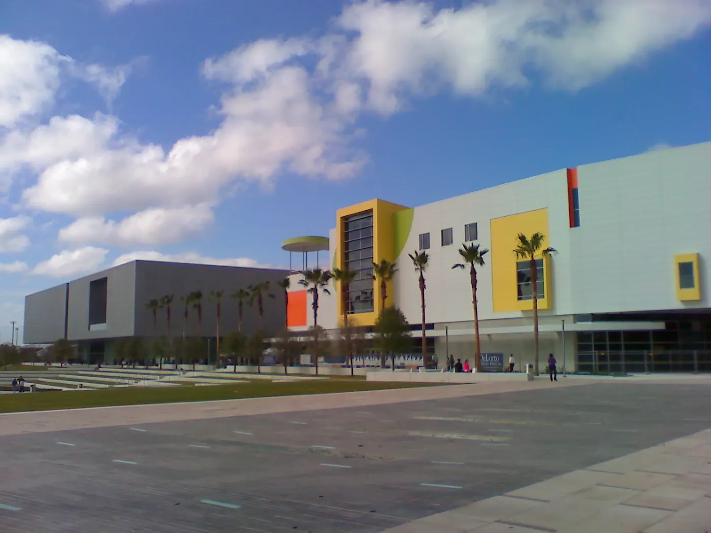 The Tampa Museum of Art's modern building on the Riverwalk, with colorful yellow and orange panels and a row of palm trees