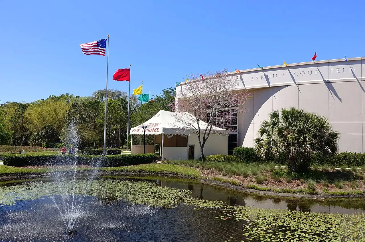 The entrance building of the Tibbals Learning Center and Circus Museum on the Ringling estate, with a fountain, flags and a "Main Entrance" tent sign in front