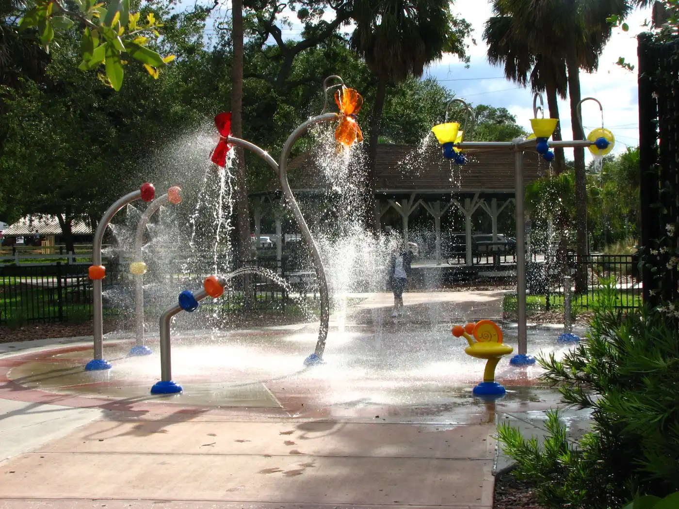 The interactive splash-pad water play area at Ballast Point Park, with a historic pavilion visible behind it