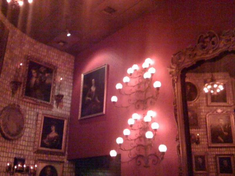 A candlelit dining room inside Bern's Steak House, with framed portraits, a mirrored wall and an ornate candelabra