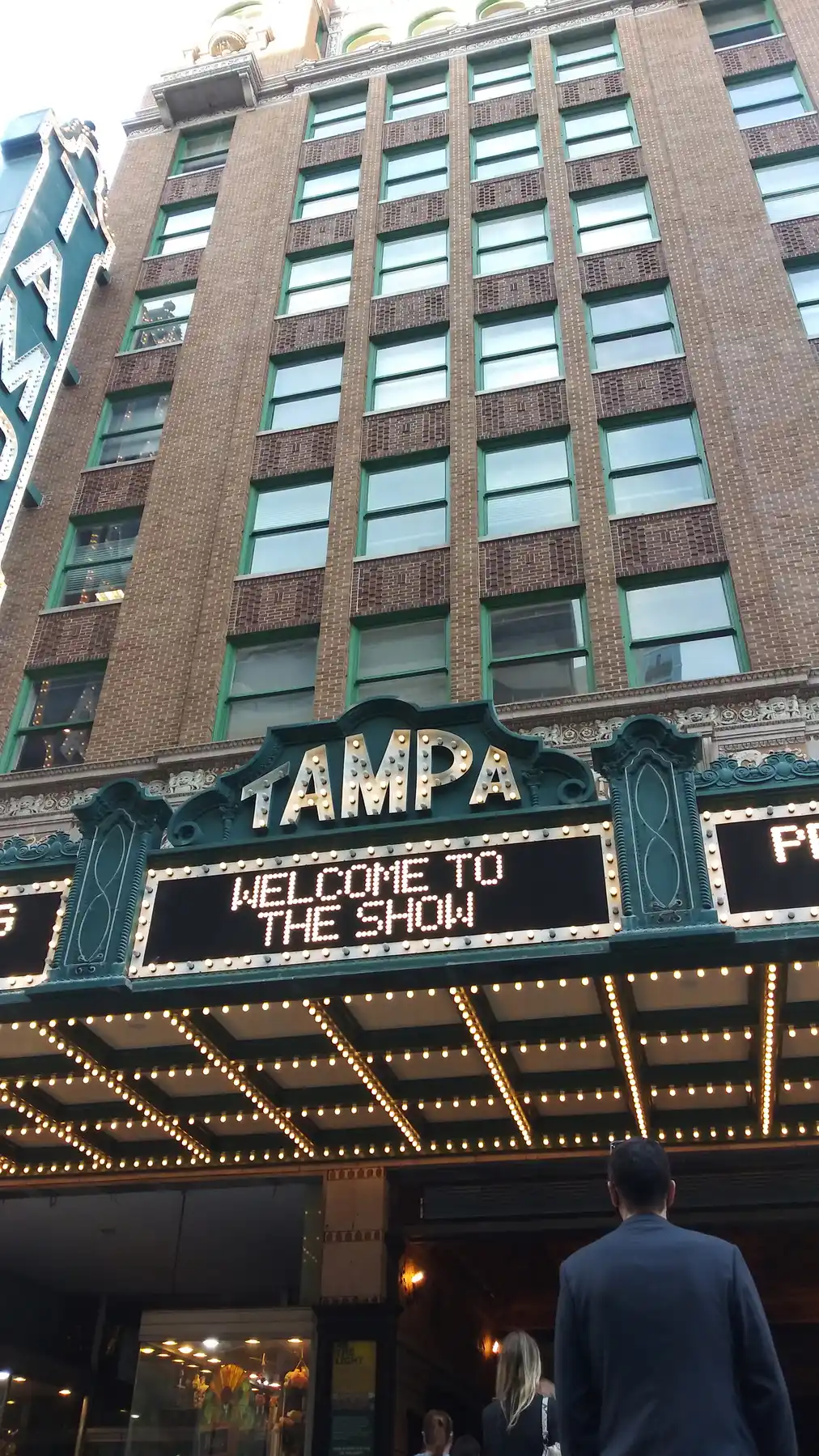 The Tampa Theatre's lit marquee reading TAMPA and WELCOME TO THE SHOW beneath the historic building's brick facade