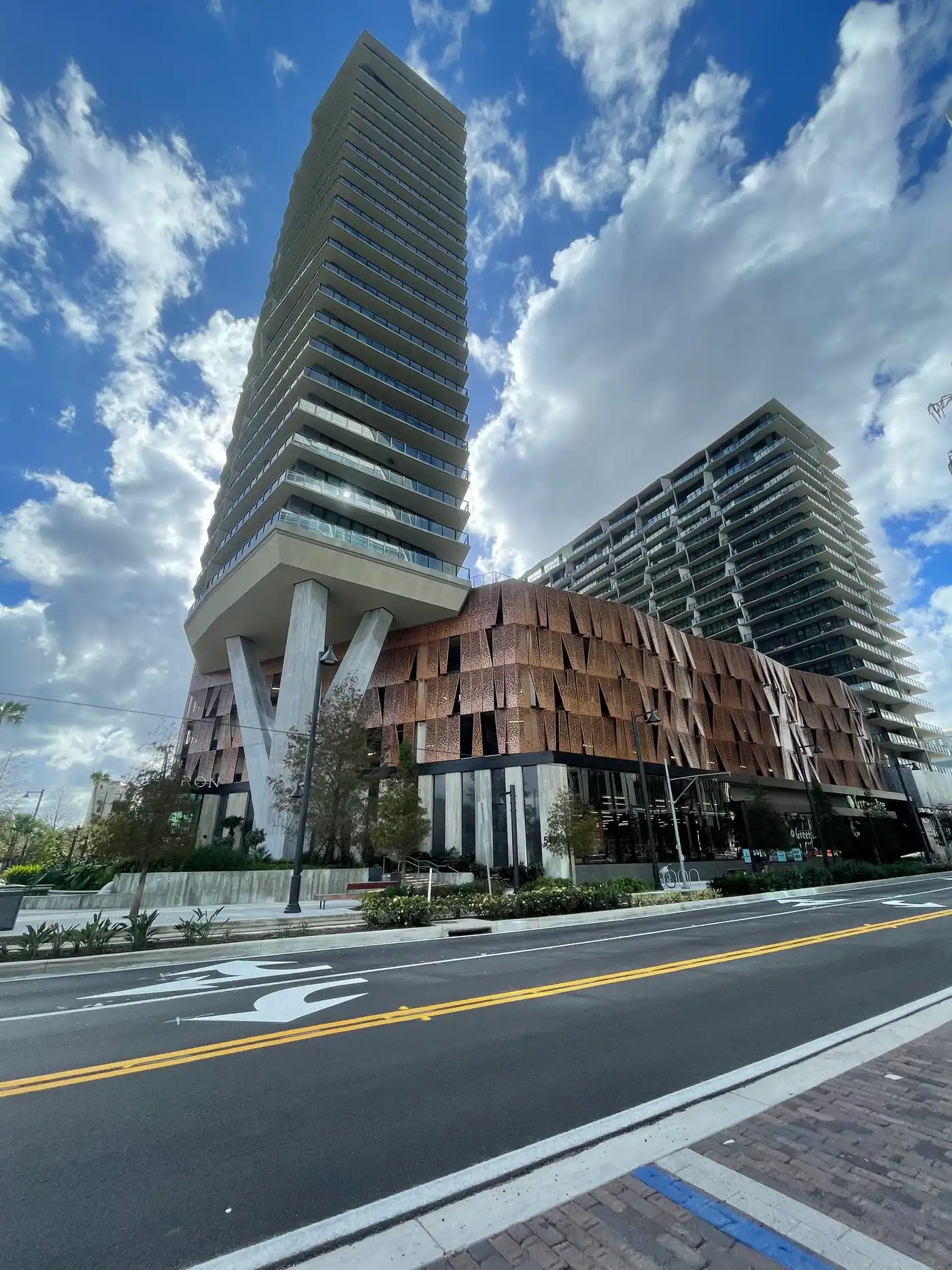 The Heron Residences tower and a neighboring building in the Water Street Tampa district, with a copper-toned podium facade