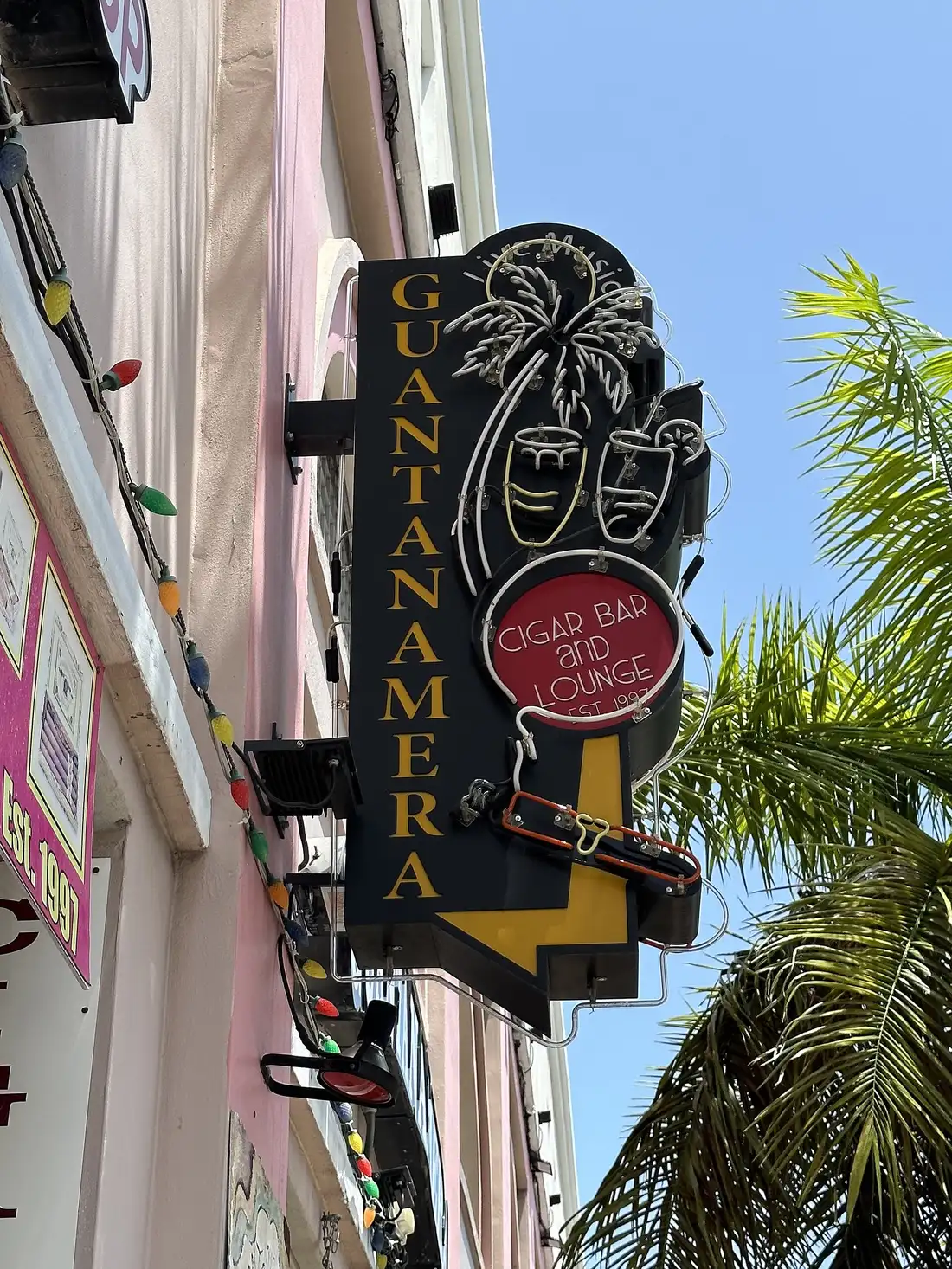 The neon "Guantanamera Cigar Bar and Lounge" sign with a palm-tree design, mounted on a building along Calle Ocho in Little Havana