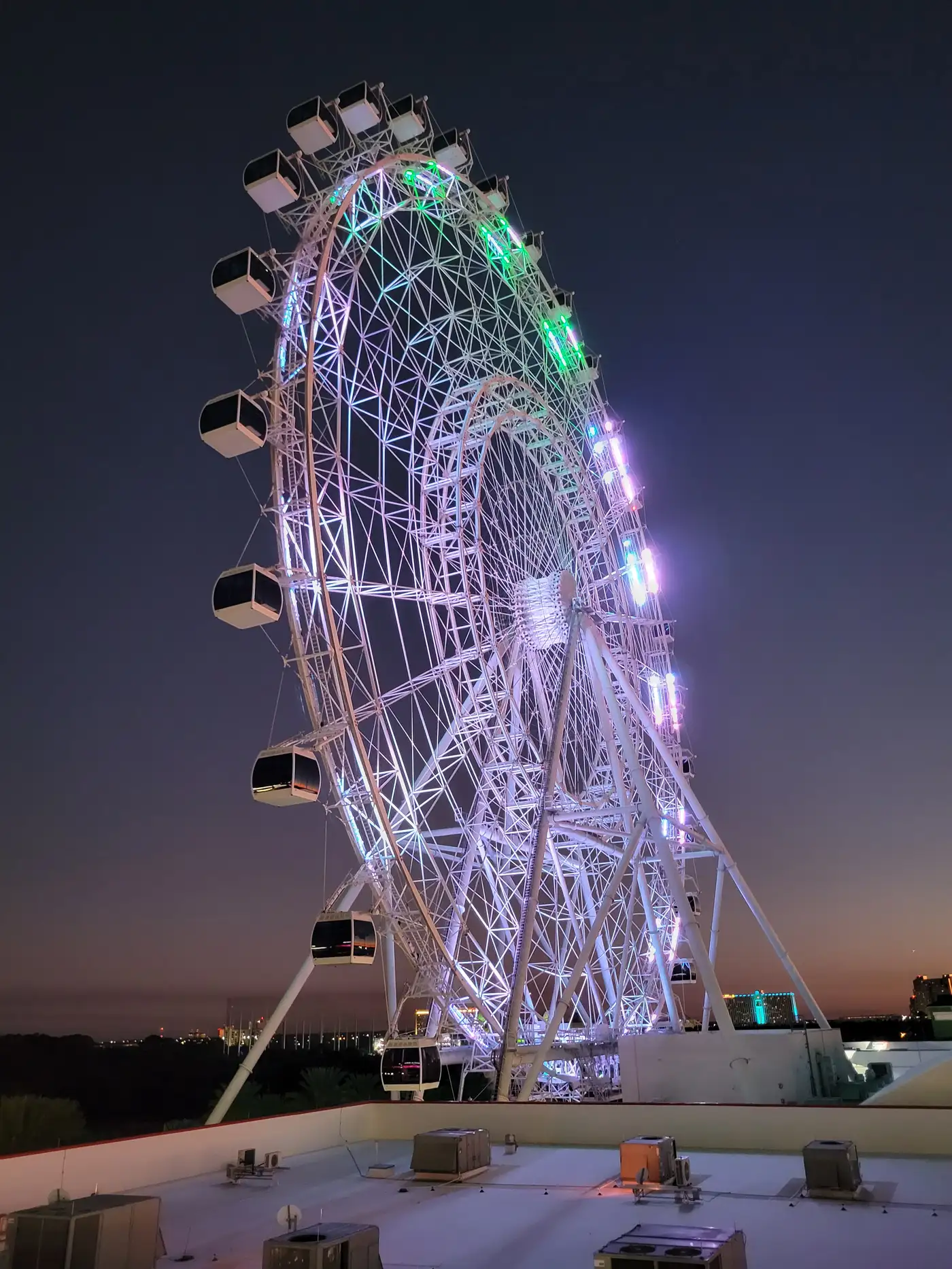 The Wheel at ICON Park lit white and green against the night sky
