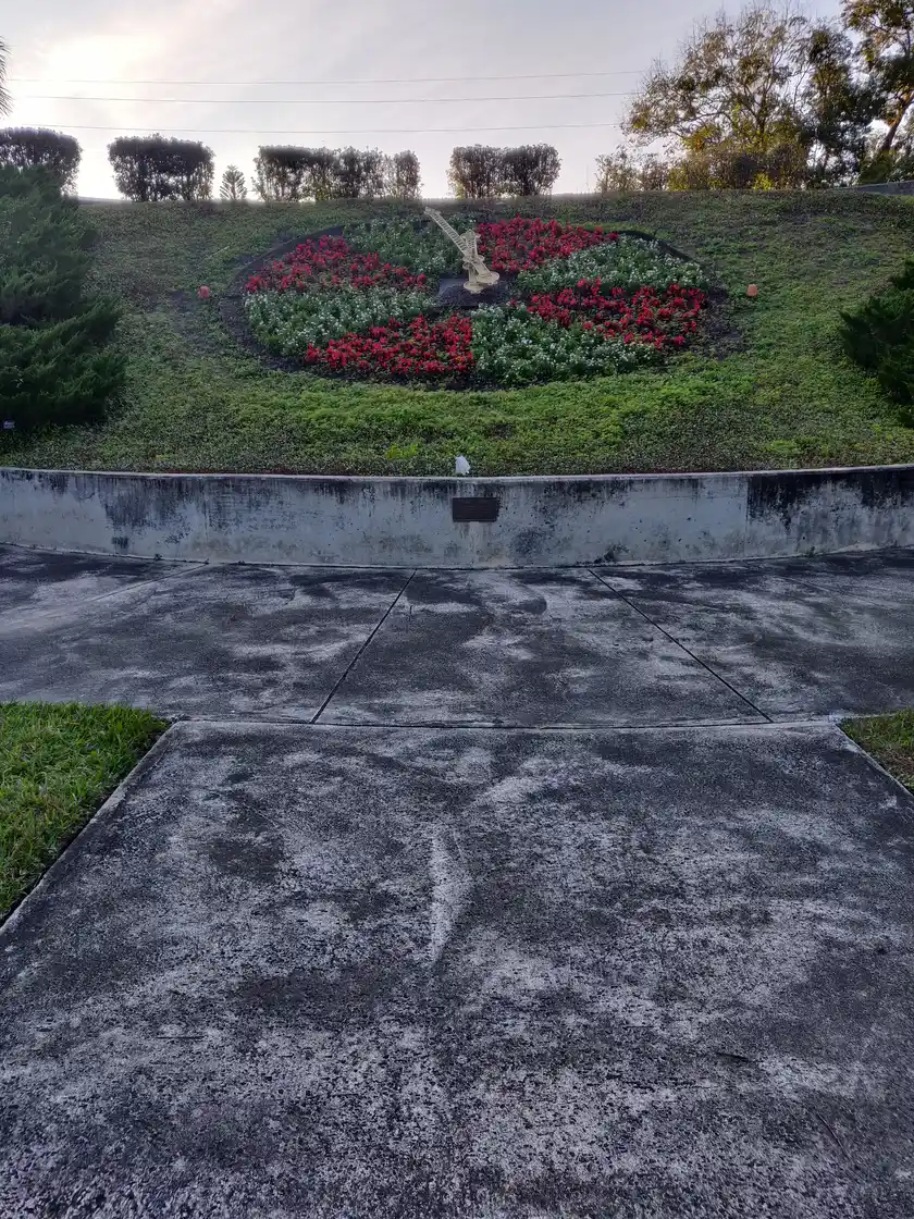 A circular floral clock planted with red and white flowers on a hillside at Harry P. Leu Gardens