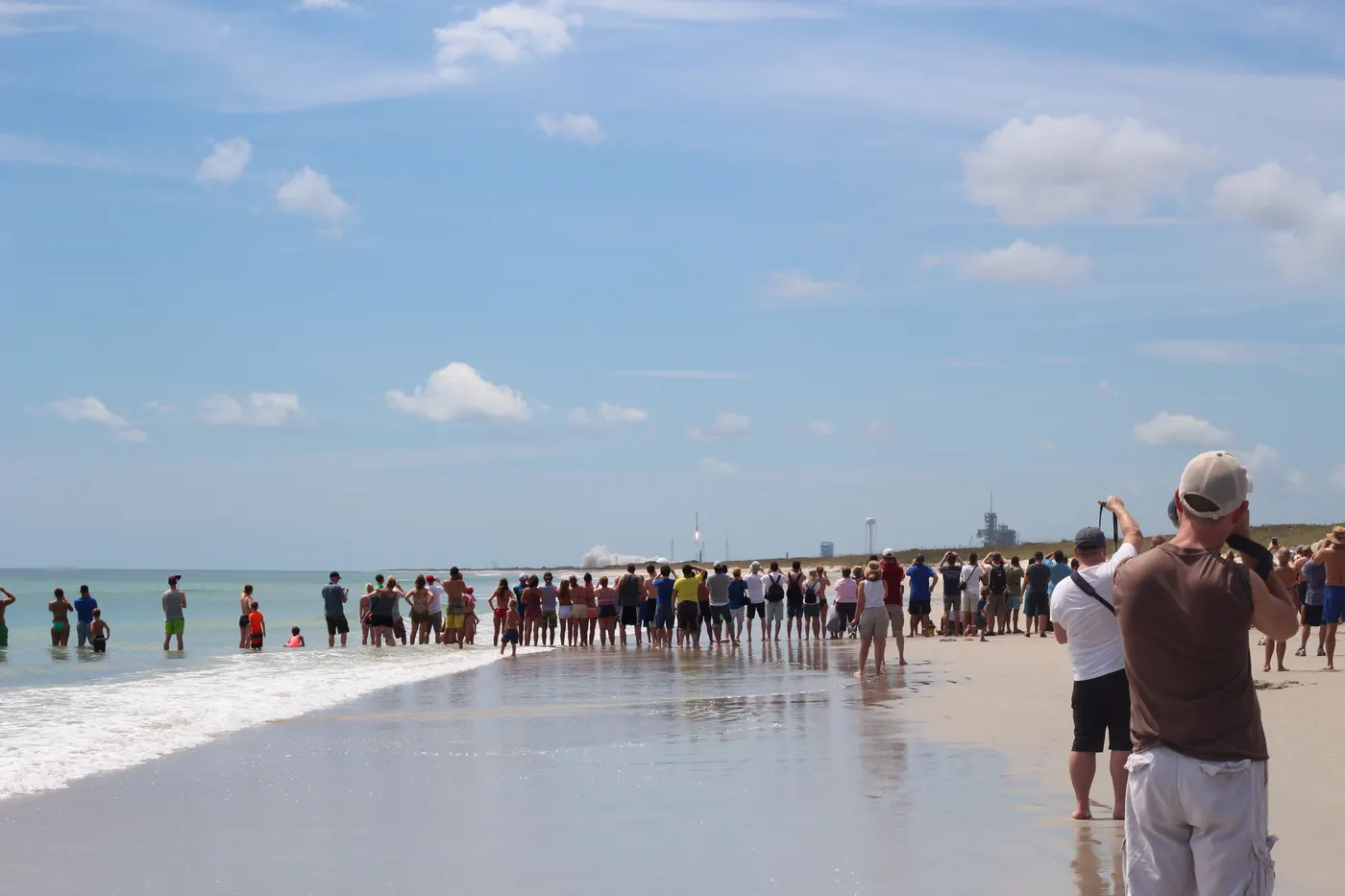 A crowd gathered on Playalinda Beach watching a rocket lift off in the distance