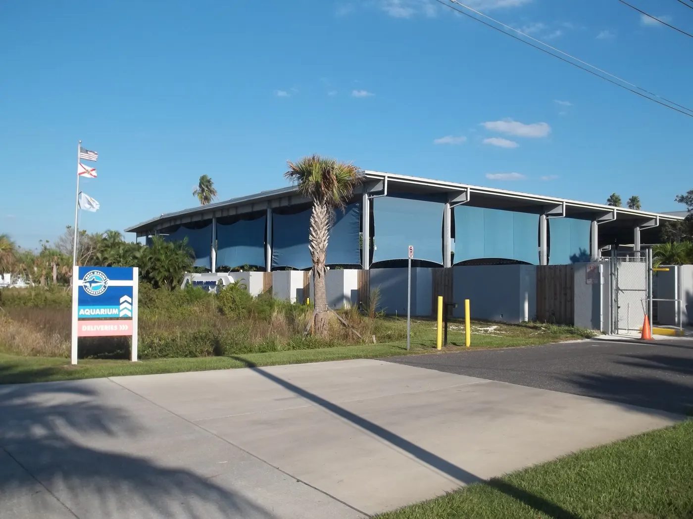 The modern curved-roof exterior of Mote Marine Laboratory in Sarasota with an entrance sign and flags out front