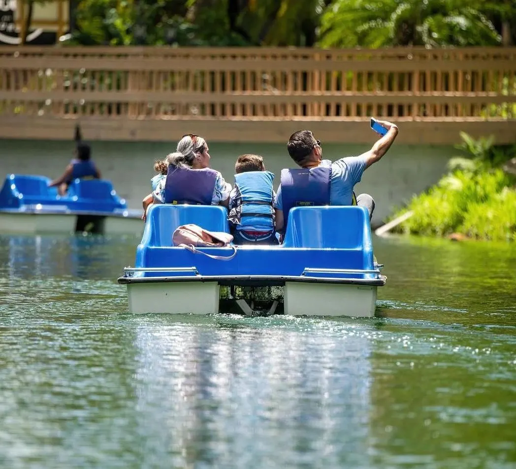 A family riding a blue paddle boat on the lake at Pinto's Farm