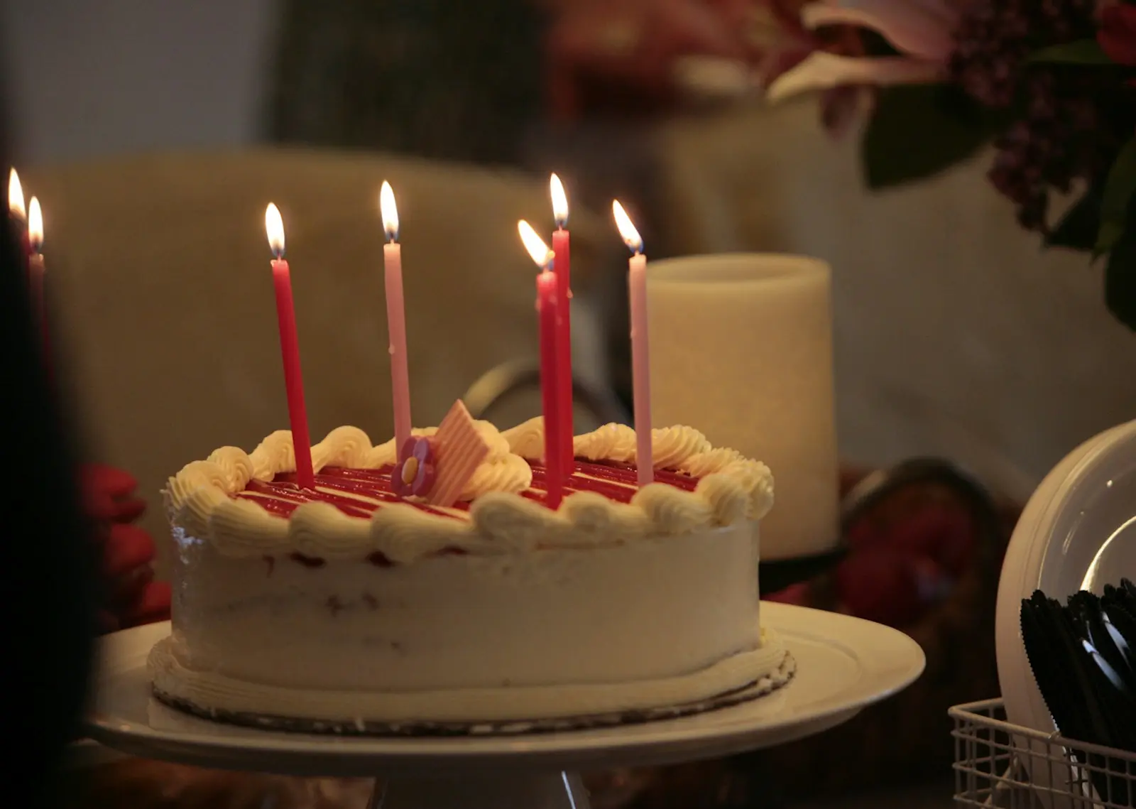 White birthday cake with five lit candles