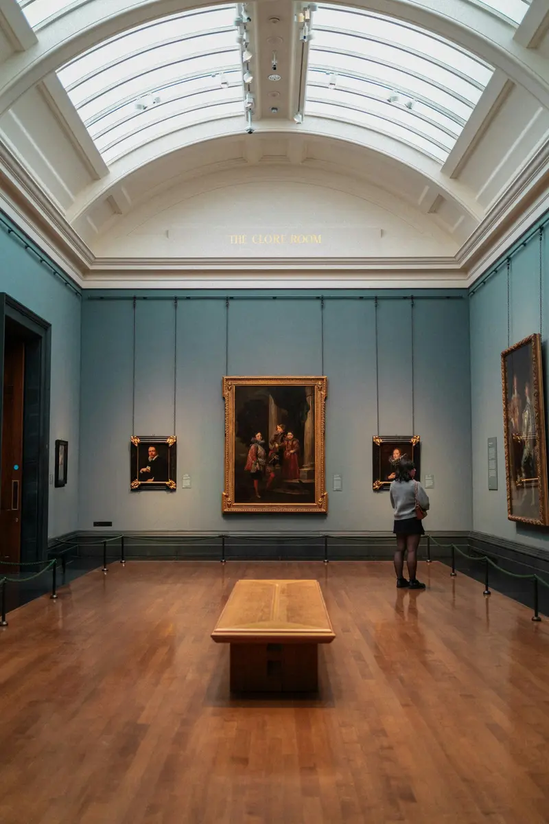 Visitor viewing framed paintings in a skylit museum gallery