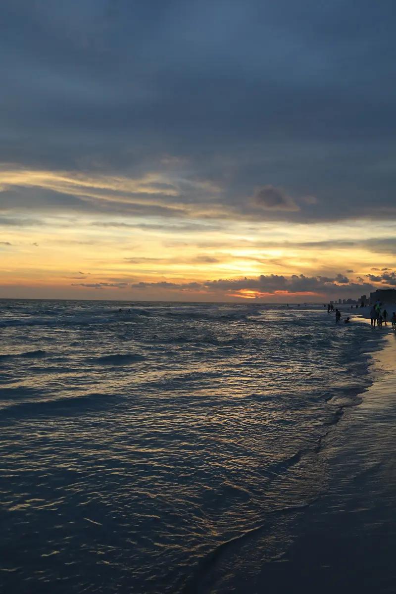People walking the shoreline at sunset in Panama City Beach