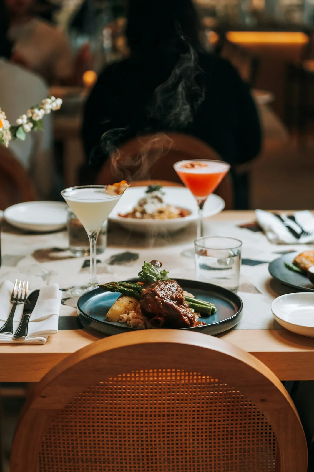Plated dinner with vegetables and cocktails on a restaurant table