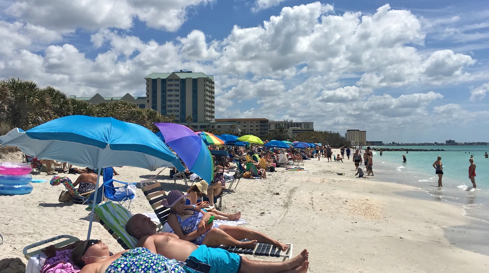 Beachgoers, colorful umbrellas, white sand, and turquoise water at Lido Key Beach